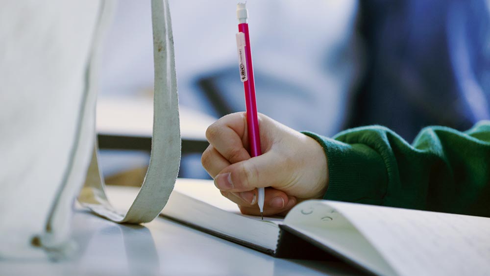 class-notes_spring2025-home close up of a students hand writing with a pencil in a notebook